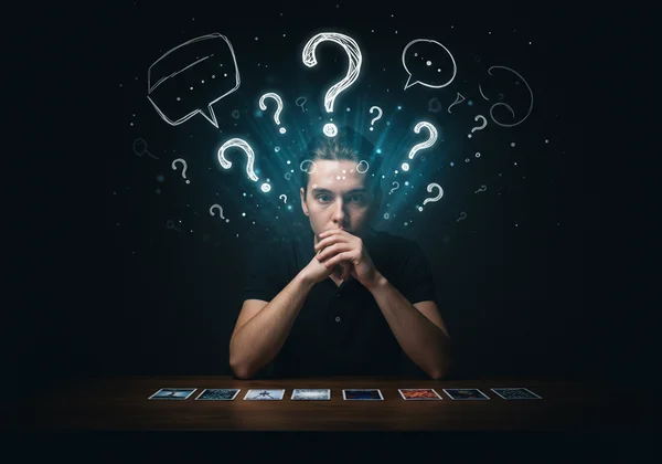 Person reflecting on questions with tarot cards for clarity.